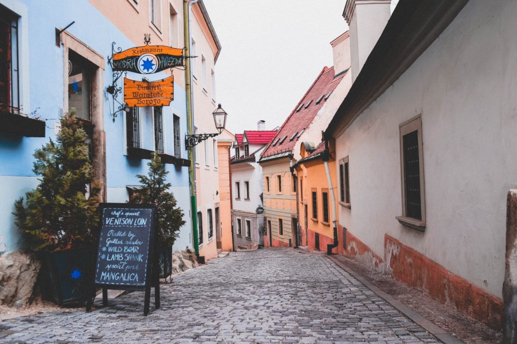 Pastel colour buildings down a cobbled street in Bratislava, Slovakia